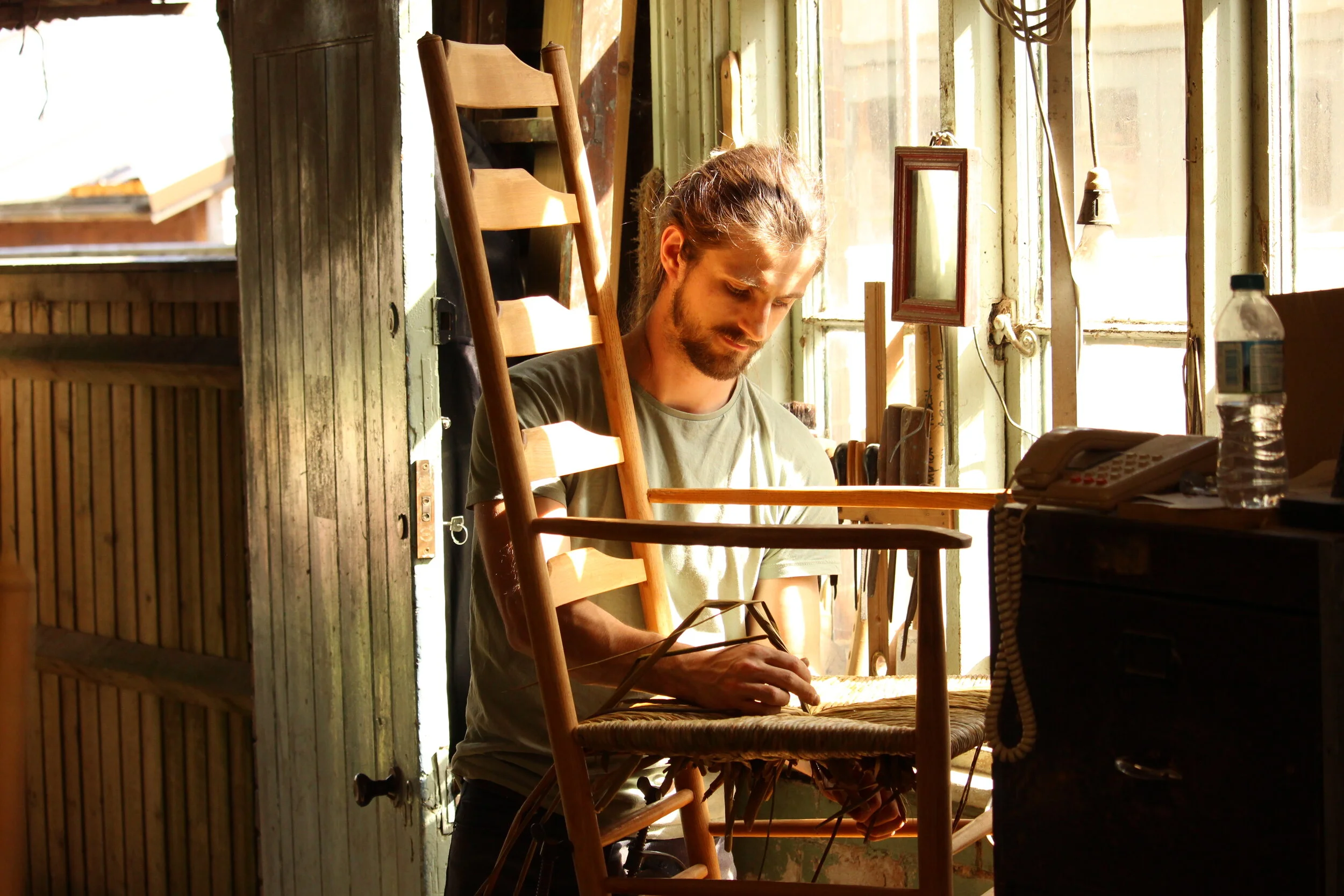 Richard Platt weaving a new rush seat onto a wooden rocking chair