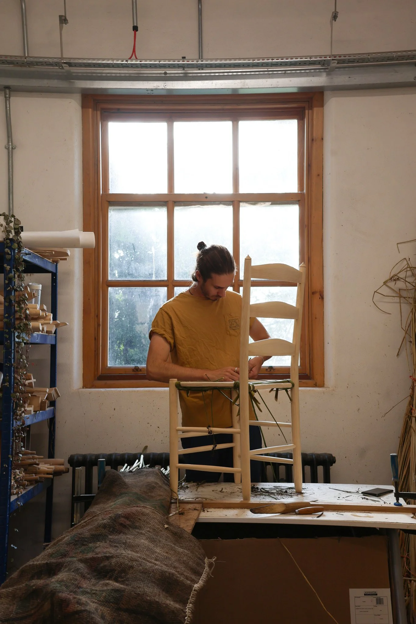 Sam Cooper weaving a rush seat onto a wooden chair frame at Marchmont Workshop