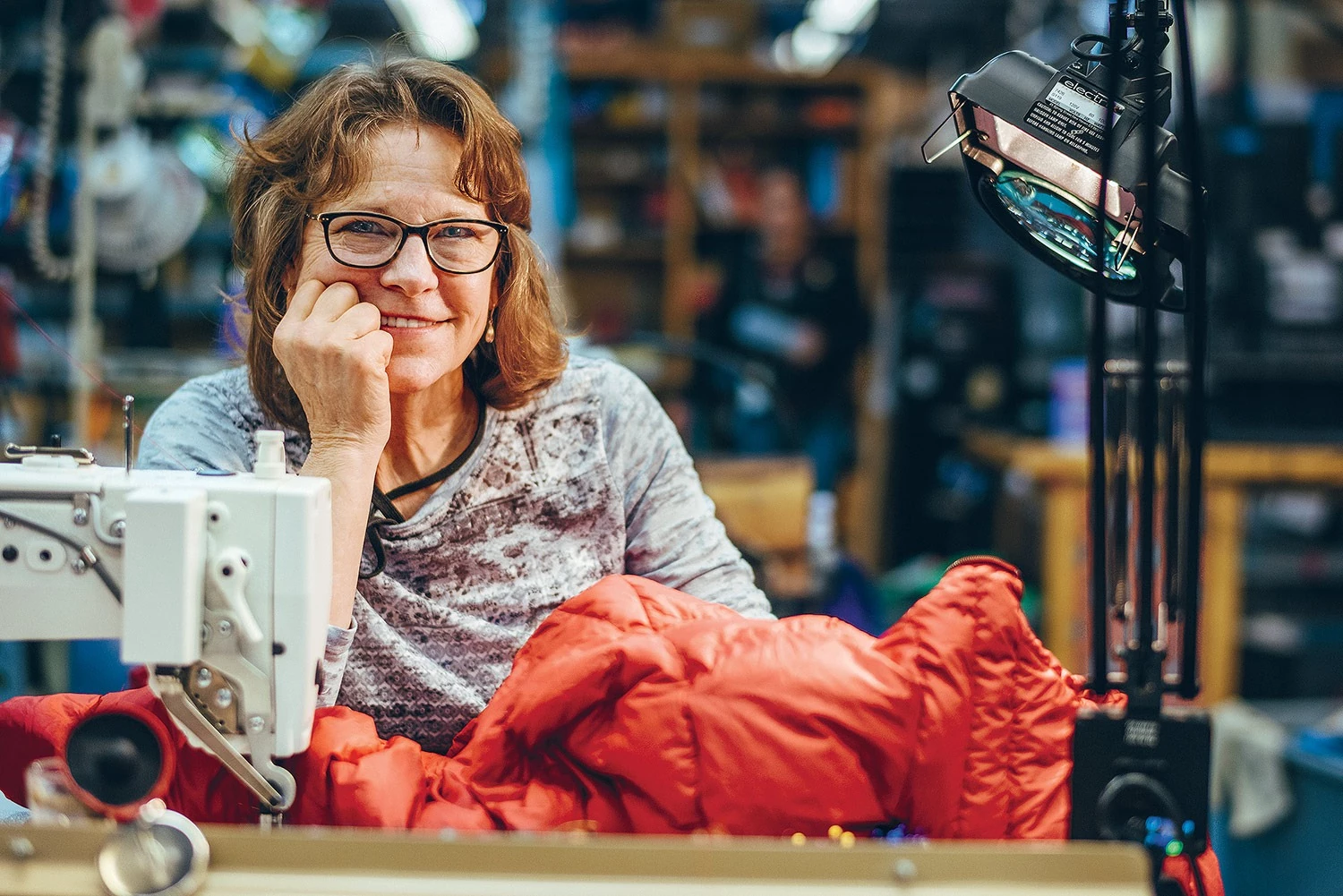 Susan Baker mending a well-used garment at an industrial sewing machine